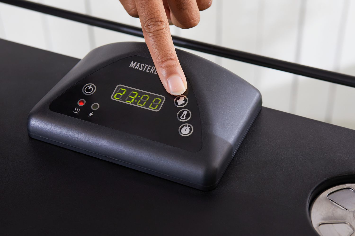 Hand pressing a button on the Masterbuilt MB20072918 40-Inch Digital Electric Smoker