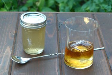A jar of homemade gomme syrup next to a cocktail