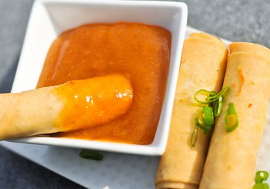 Fried egg roll being dipped in homemade duck sauce