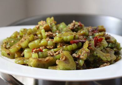 Stir fried bitter melon with ground pork and chiles on a platter. 