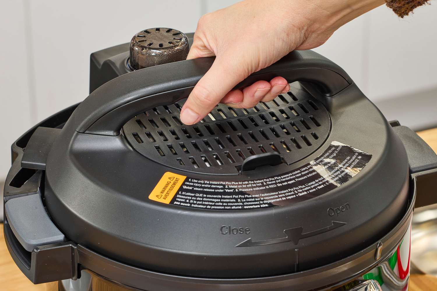 A person removes the lid from the Instant Pot Pro Plus Wi-Fi Smart 10-in-1 6-Quart Pressure Cooker