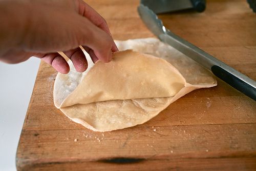 A hand lifting two thin pancakes to separate them where they've stuck together.