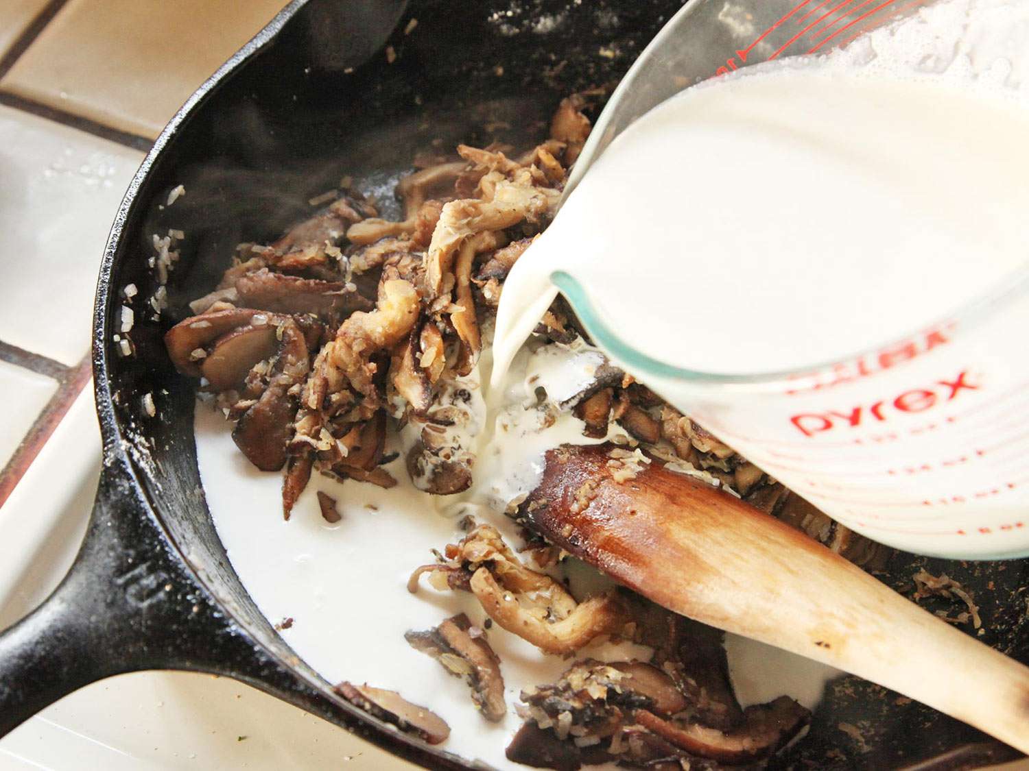 Adding cream to skillet with mushrooms and aromatics.