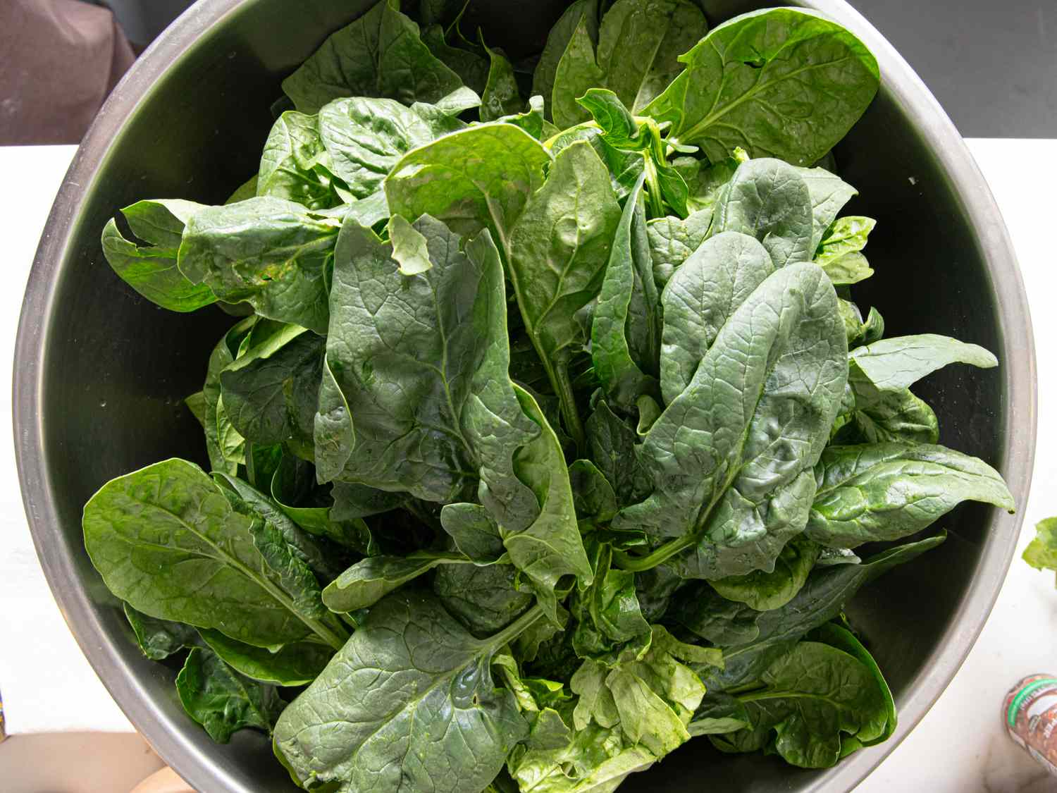 Fresh spinach leaves in a metal bowl