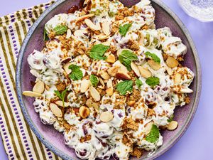 Grape Salad with fresh mint leaves on a purple surface, with a purple striped towel.