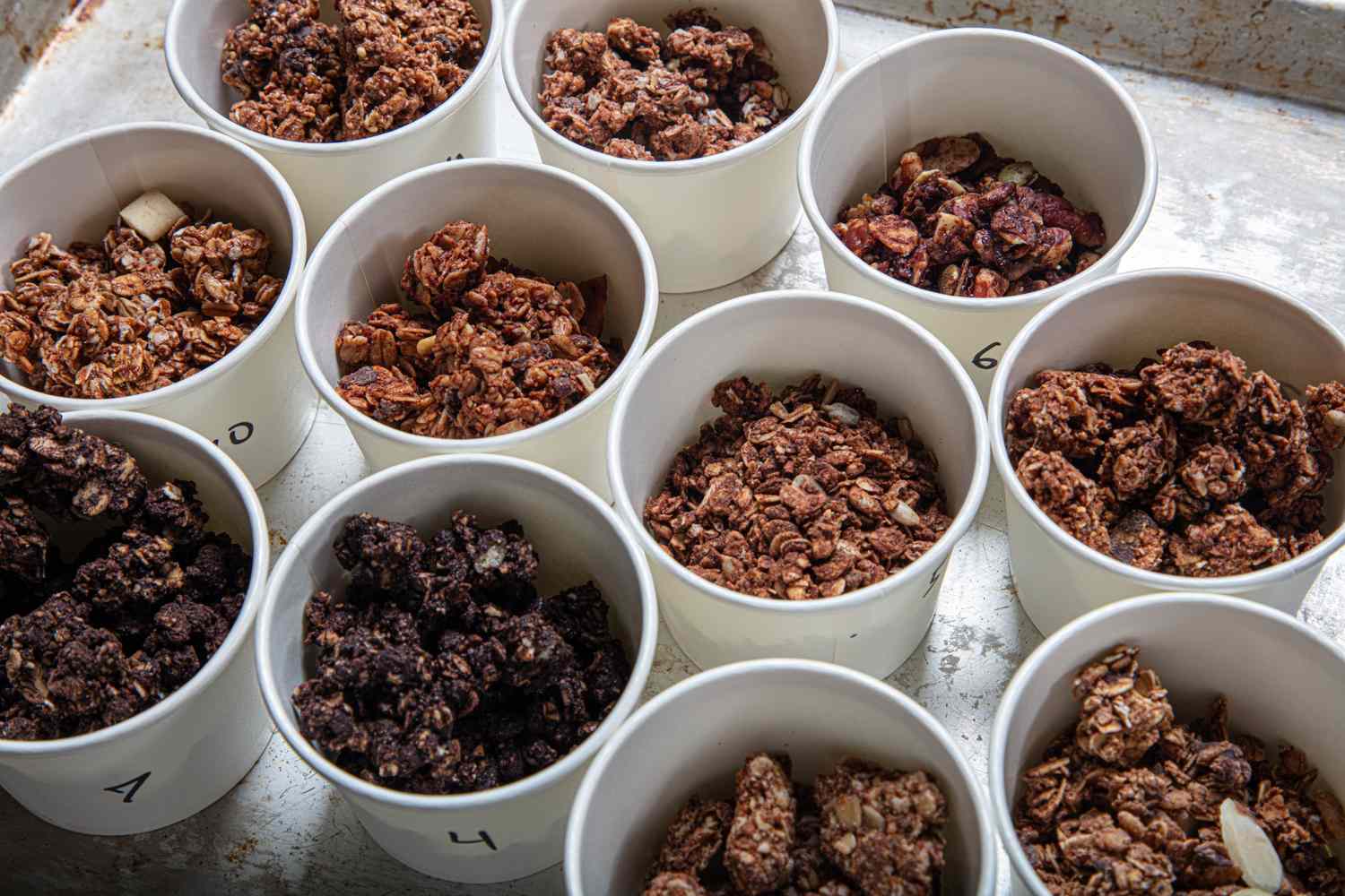 A selection of granola samples in labeled cups on a tray part of a taste test setup