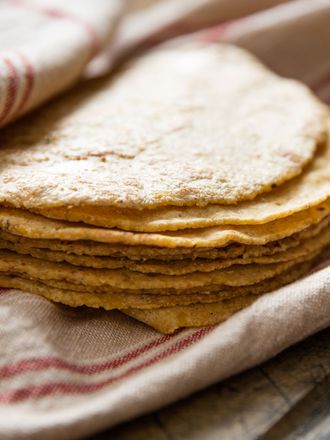Stack of corn tortillas wrapped in a kitchen towel. 