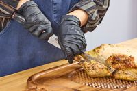 A person cuts a chicken with the Miyabi Mizu SG2 9.5 Inch Slicing Knife