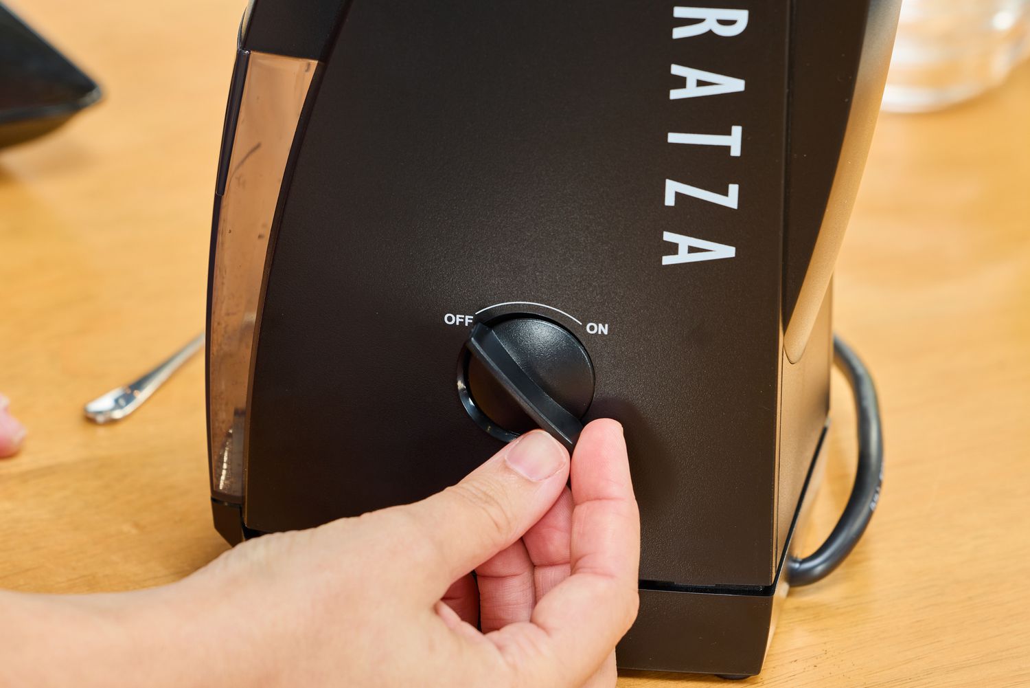 A person turns the dial on the Baratza Encore Conical Burr Coffee Grinder