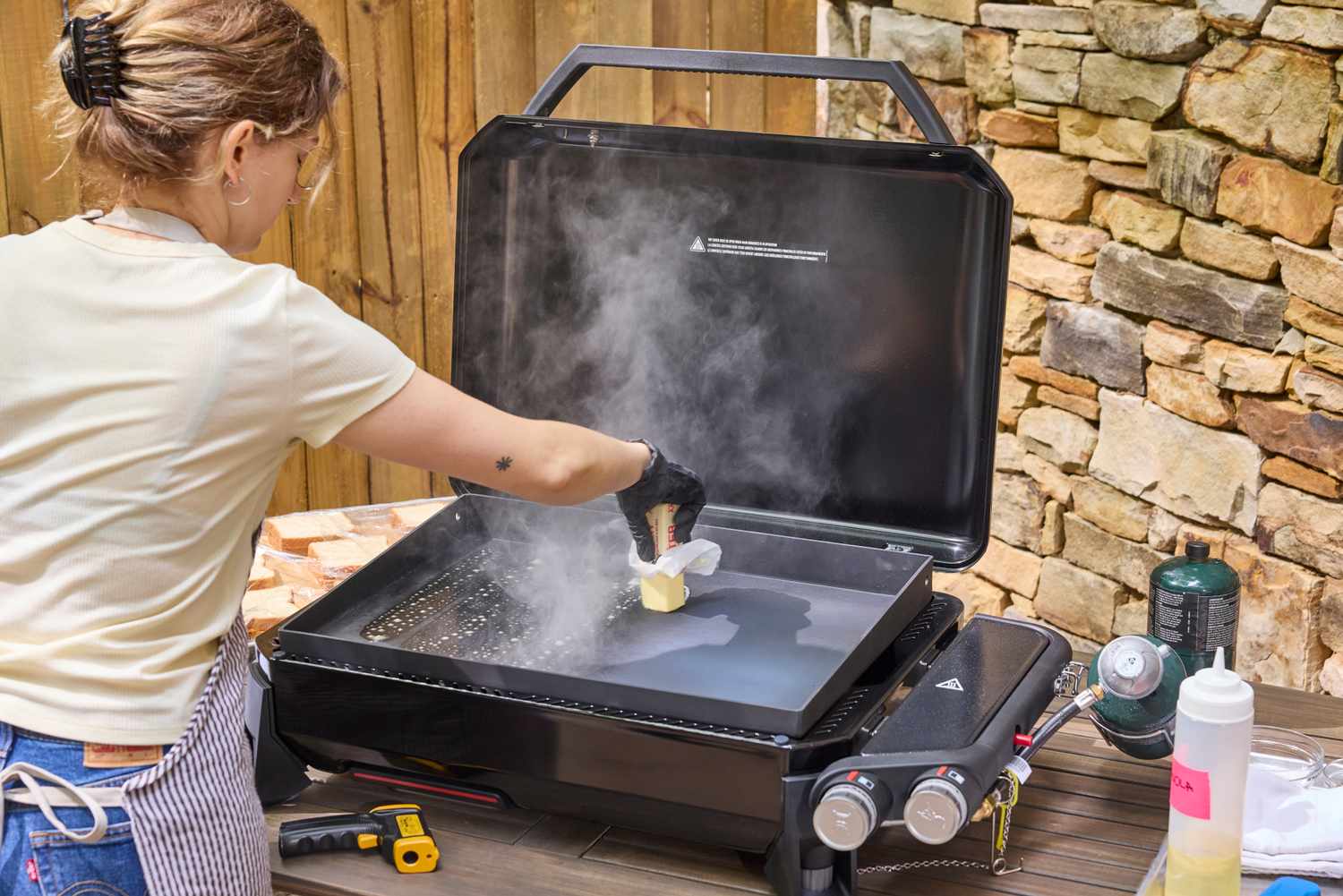 A person butters the top of the Weber Slate 22 inch Rust-Resistant Tabletop Griddle