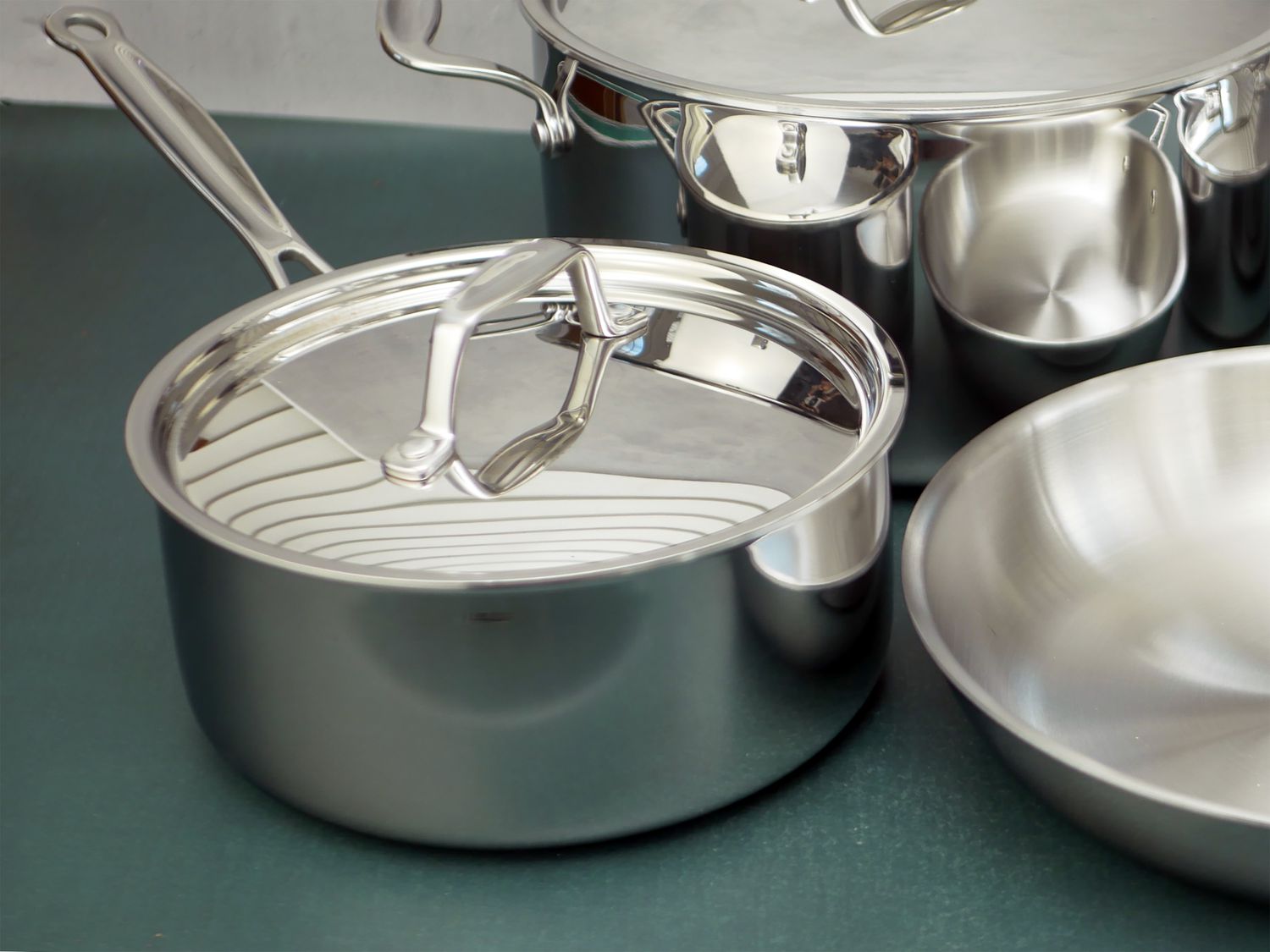 a closeup image of the goldilocks 3 quart saucepan with lid next to the other pieces in the set