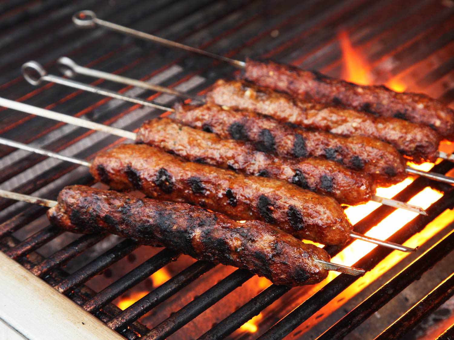 Seekh kebab on a grill. The exterior has turned golden brown and charred. 