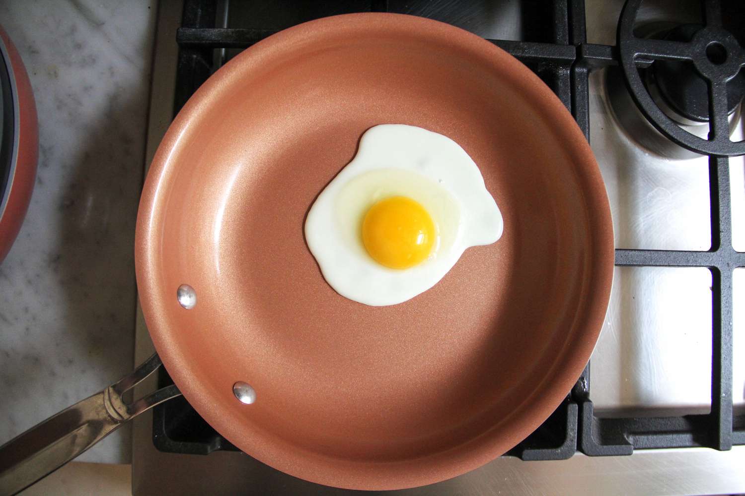 An egg frying on the BulbHead Red Copper 10-Inch Pan