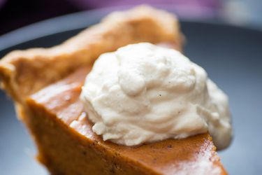Closeup of brown sugar whipped cream dolloped on a slice of sweet potato pie.
