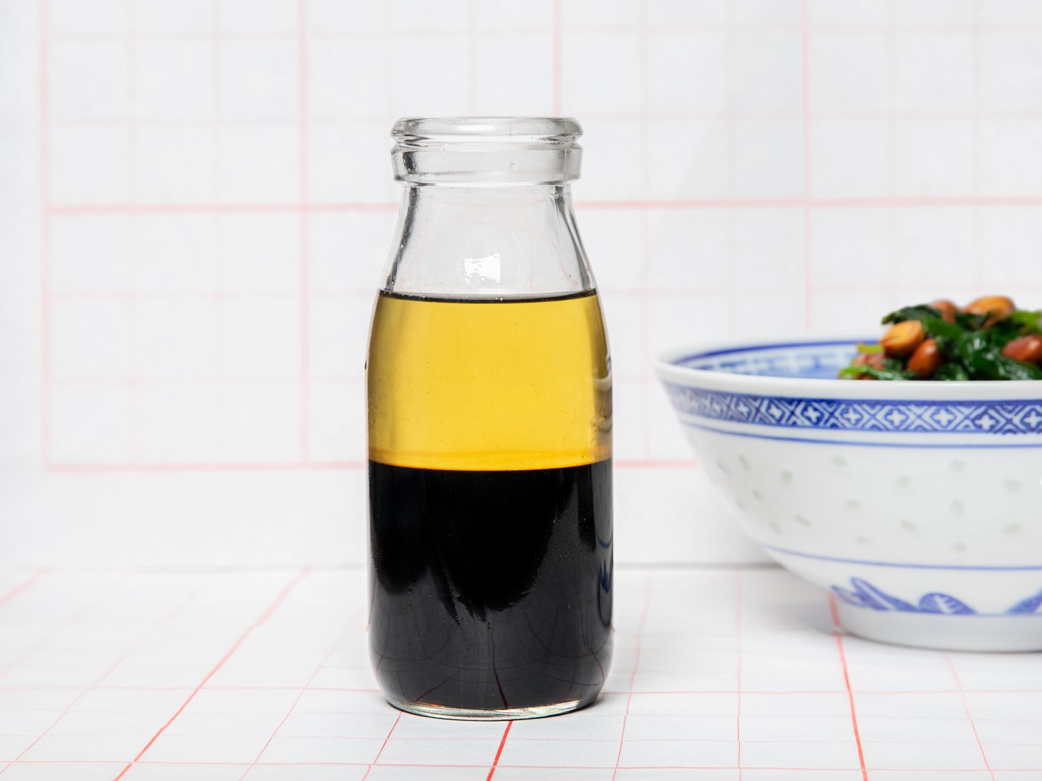 All-purpose Chinese Vinaigrette in a glass bottle on a white backdrop next to a salad 