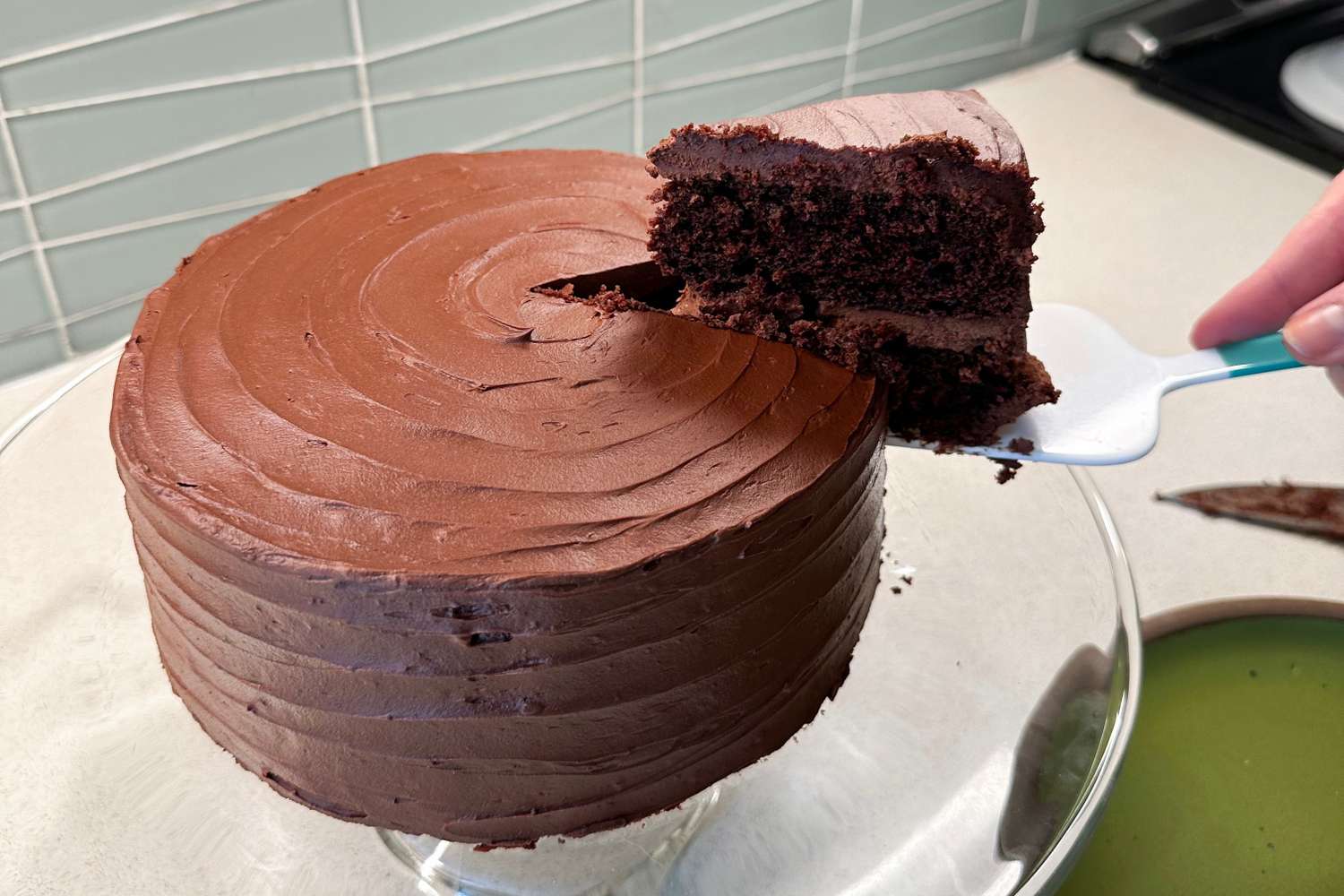 A closeup image of a chocolate cake on a glass cake stand