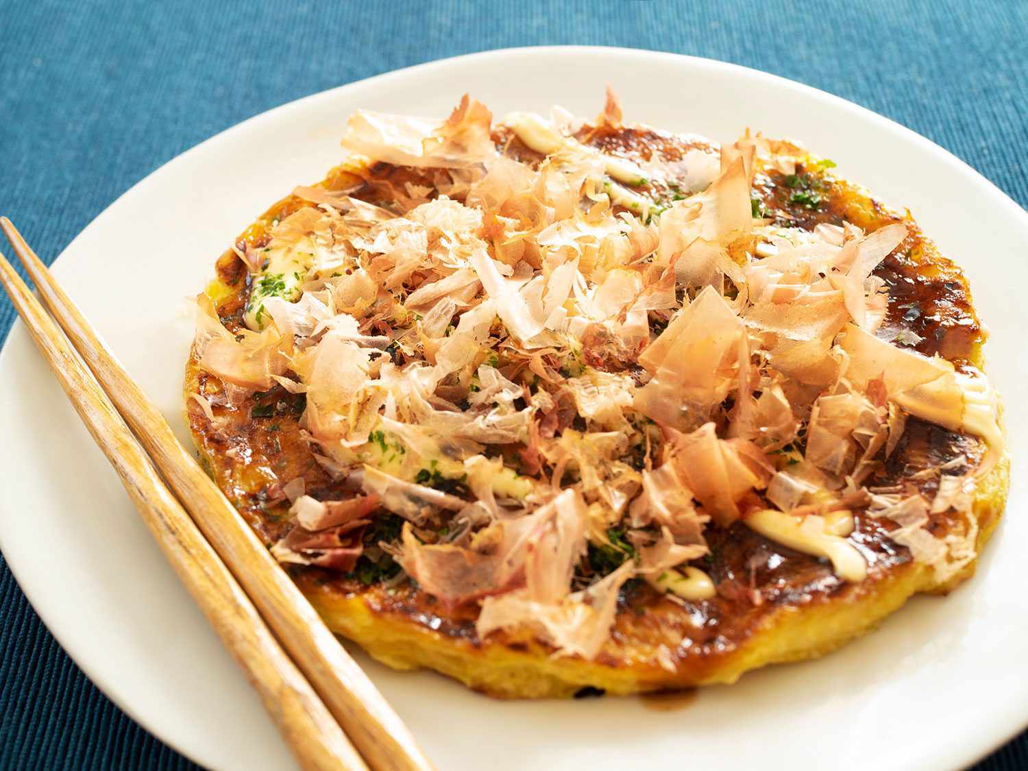 Okonimiyaki on a plate with chopsticks.