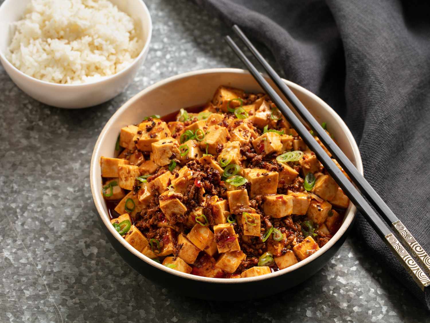 A bowl of mapo tofu, served with rice on the side.