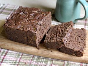 Closeup of gluten-free chocolate zucchini bread being sliced on a slender cutting board.