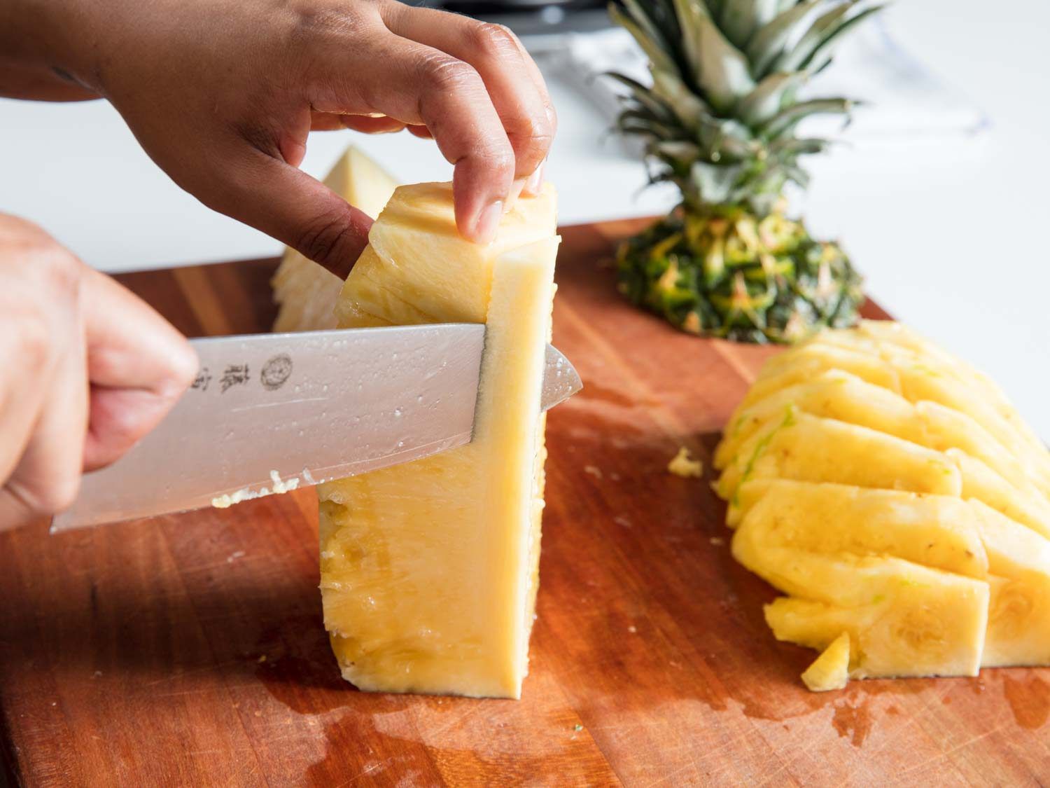 A knife trimming out the core of a pineapple.