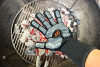 A person places their hand over coals while wearing the Blackstone Griddle Gloves