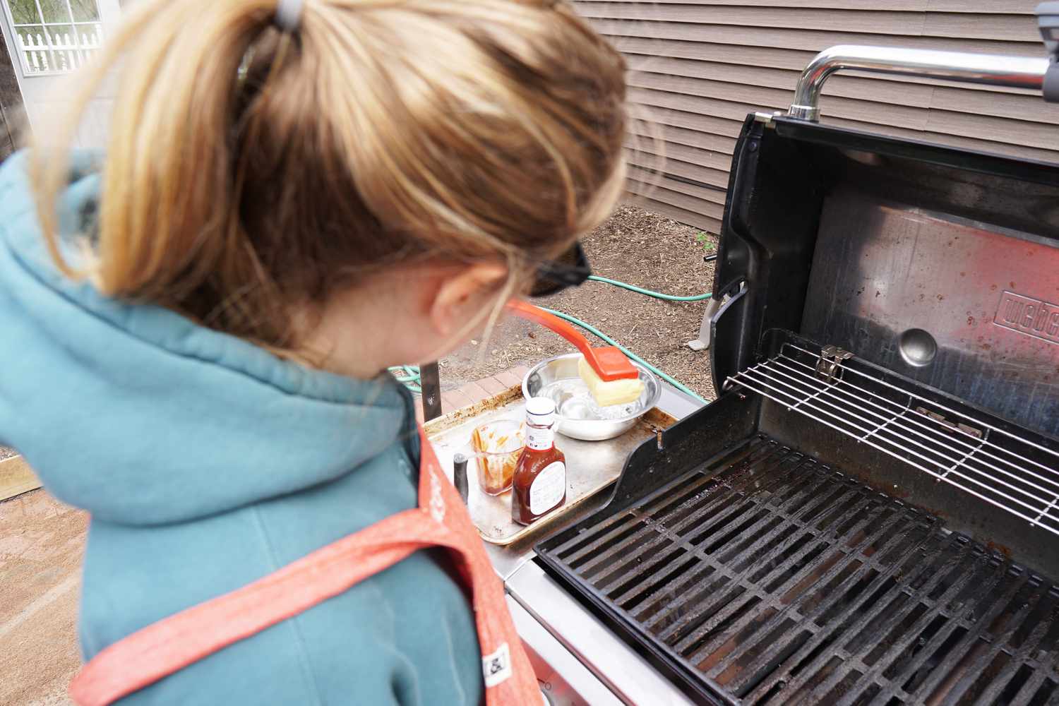 A person dipping a grill brush in water