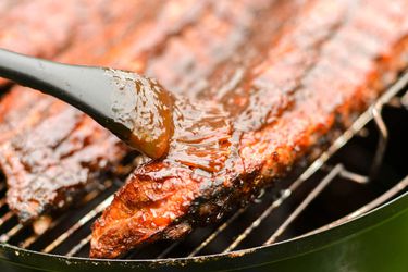 Balsamic barbecue sauce is used to glaze ribs as they cook on the grill.
