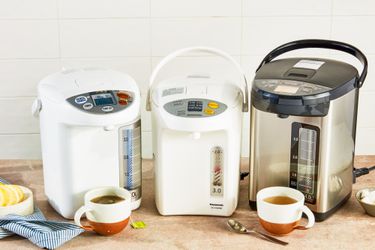 Three hot water dispensers on a wooden countertop.