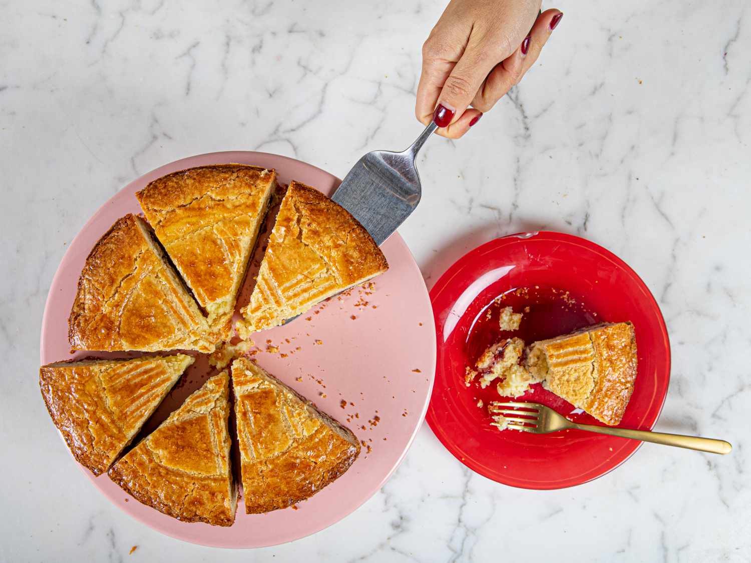 Overhead view of a hand serving a piece of gateau basque