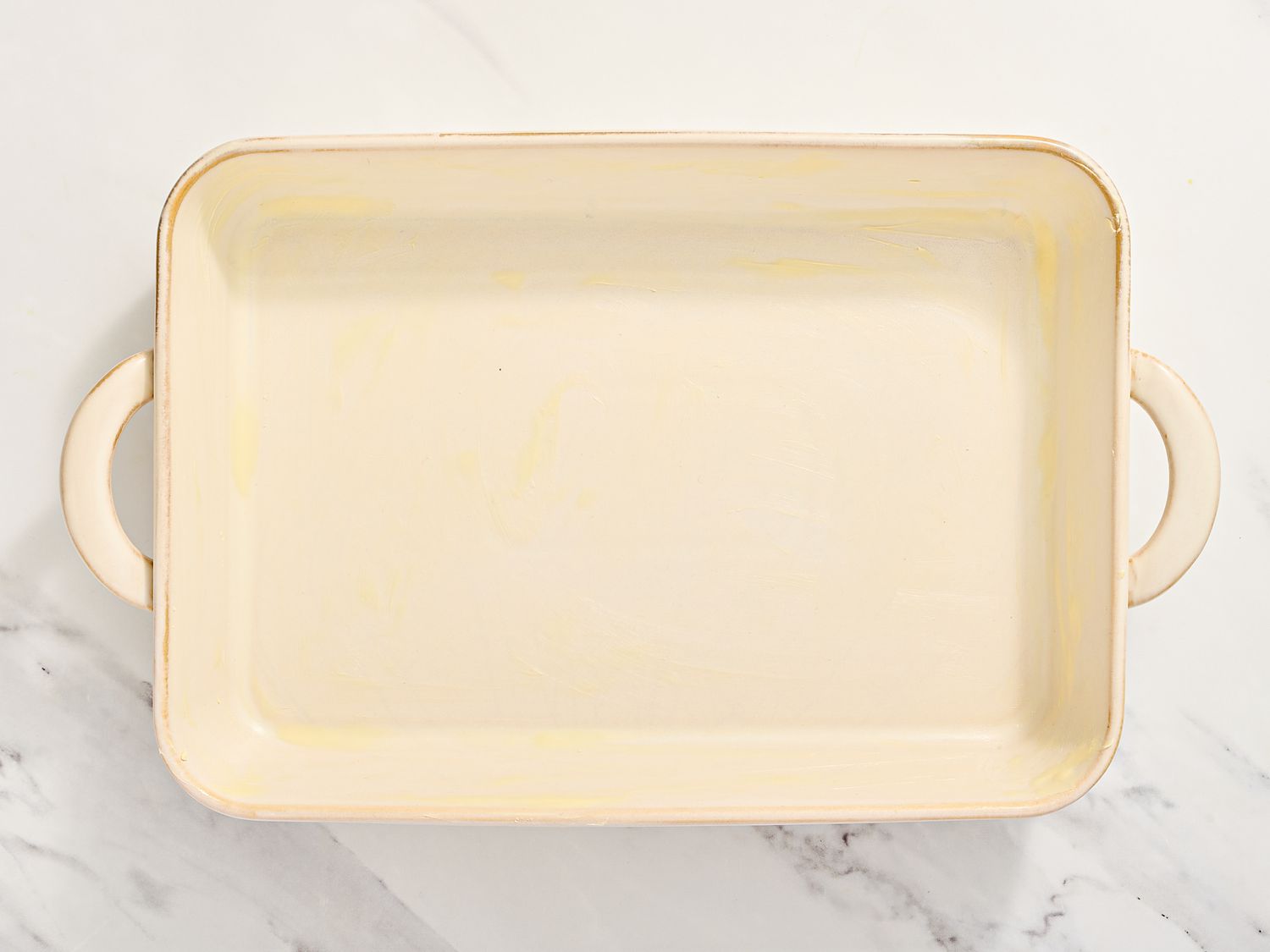A rectangular baking dish with handles, set on a marble surface