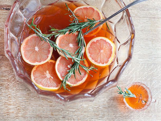 Punch bowl of rosemary-Aperol cocktail with citrus slices.