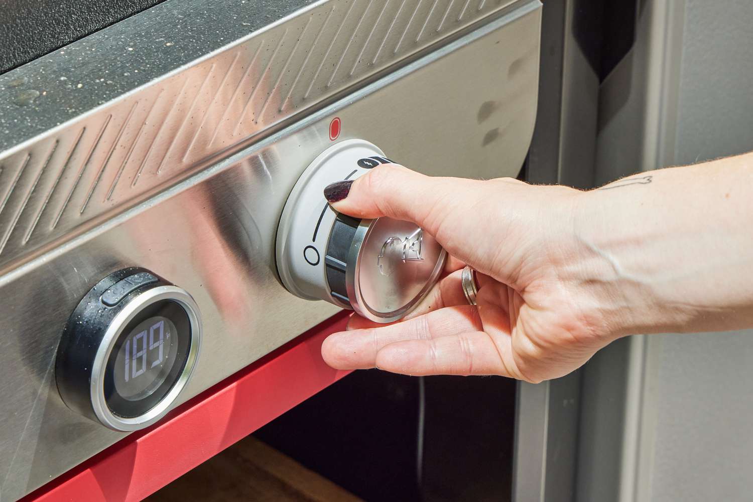 A person adjusts the temperature on the Weber Slate 30 Inch Griddle