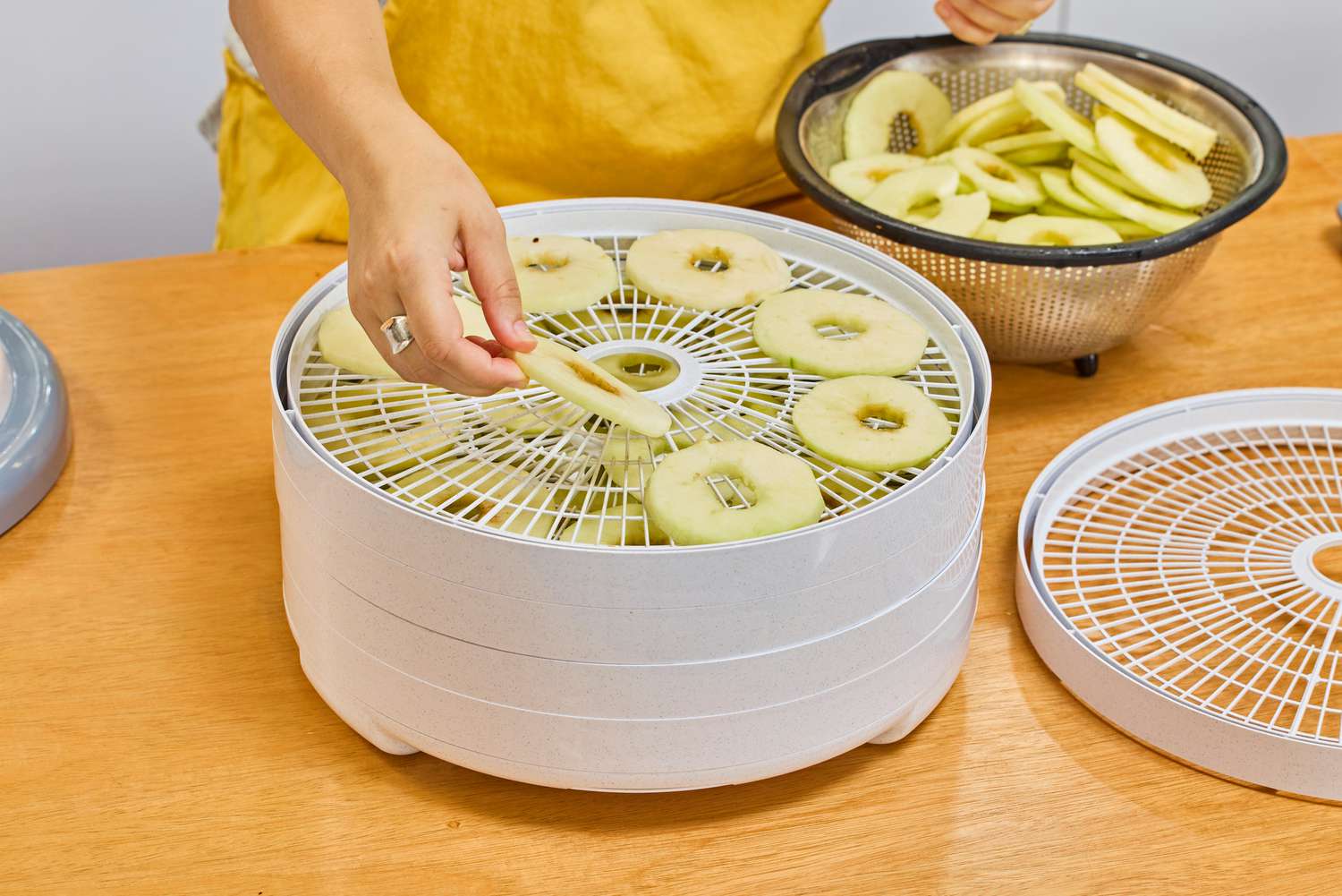 A person placing food inside Nesco Snackmaster Pro Food Dehydrator
