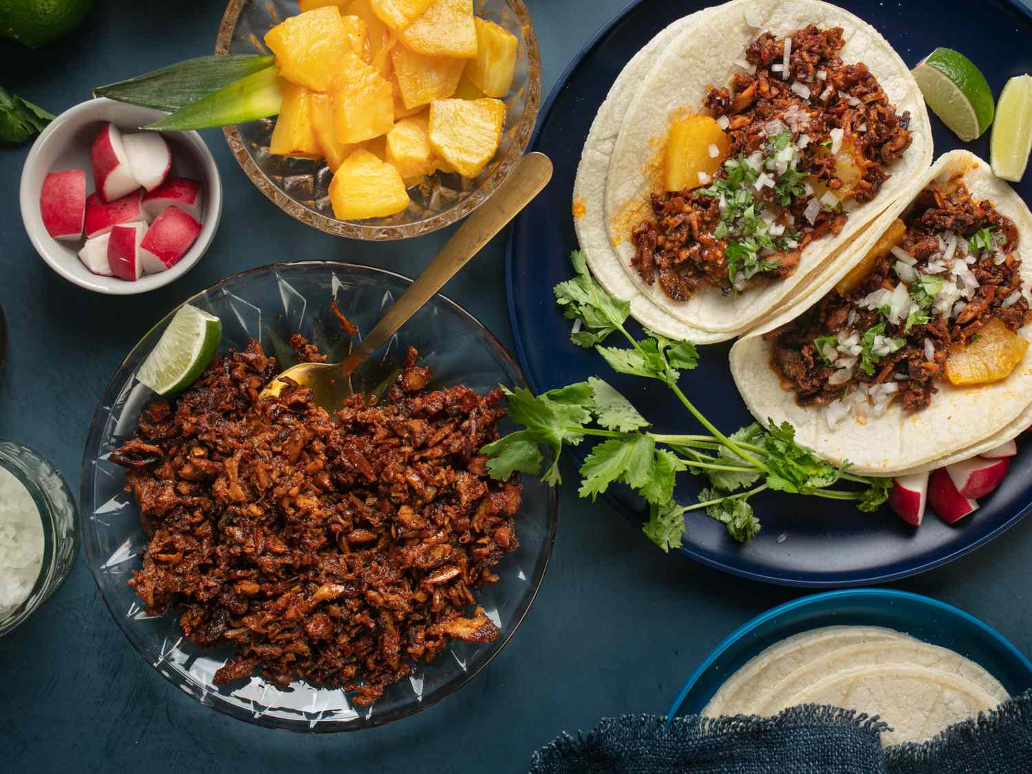 Chopped al pastor meat, radishes, roasted pineapple chunks, and assembled tacos