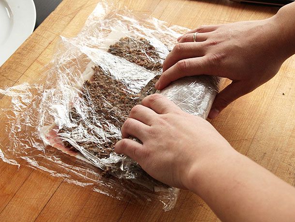 Wrapping beef tenderloin in duxelles, prosciutto, and phyllo dough to make beef Wellington.