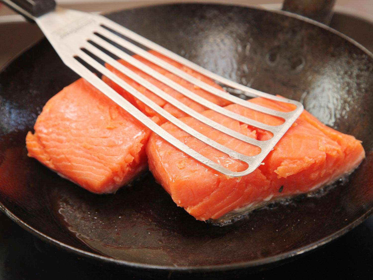 Searing two salmon fillets, skin-side down, in a carbon steel skillet after cooking sous vide.