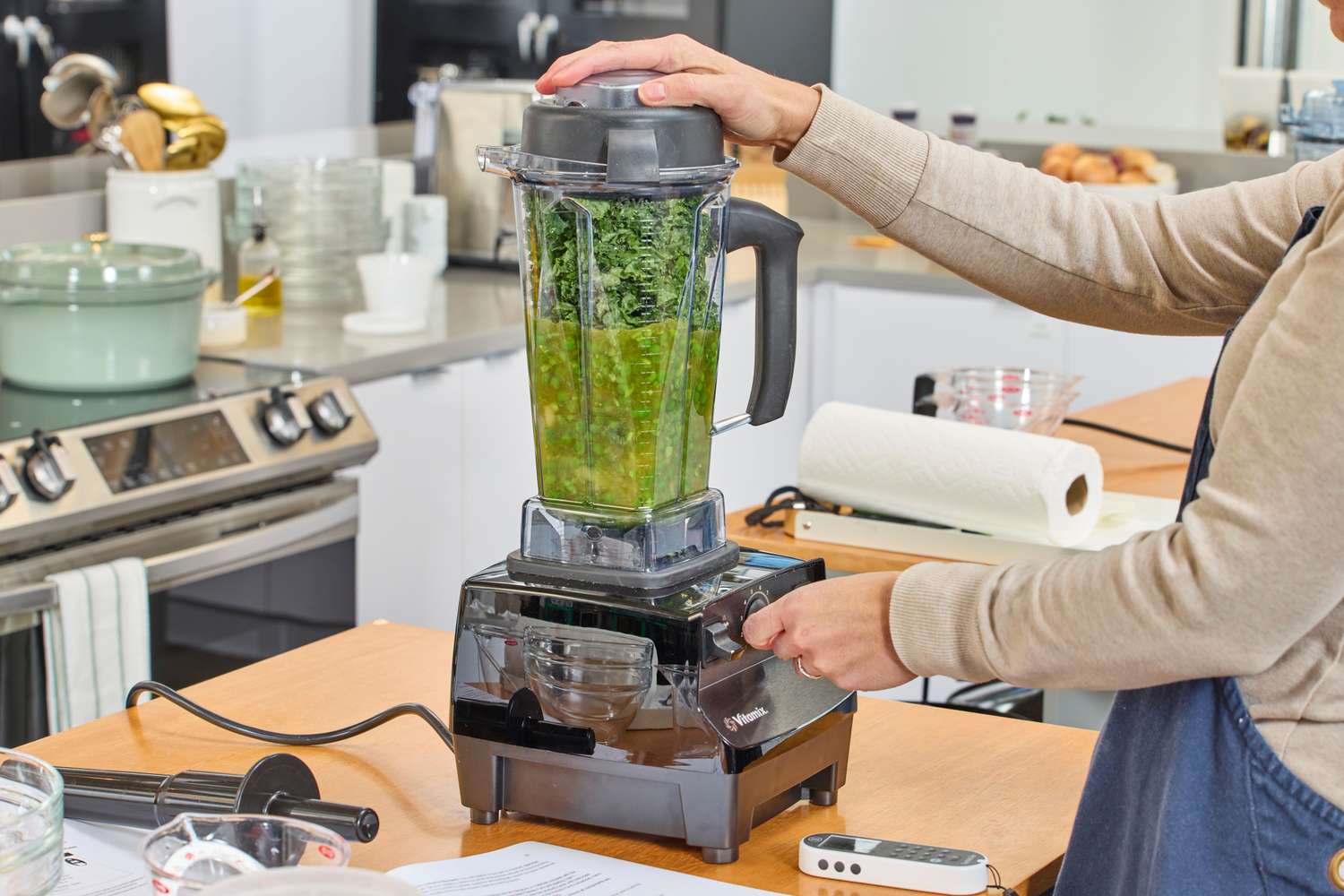 A person using the Vitamix 5200 Professional-Grade Blender to blend green items