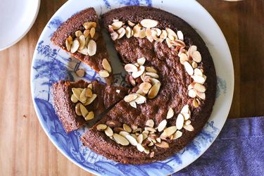 A top-down shot of the finished almond cake on a blue plate. The cake is already partially sliced.