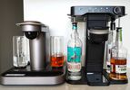 The Bartesian and Bev cocktail machines adjacent to each other on a kitchen counter.