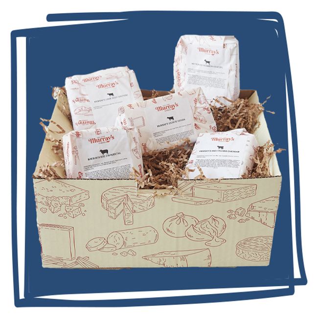 A selection of cheeses arranged in a box filled with shredded paper for packaging
