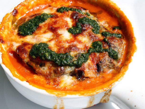 Closeup of eggplant tian, dolloped with pistou.