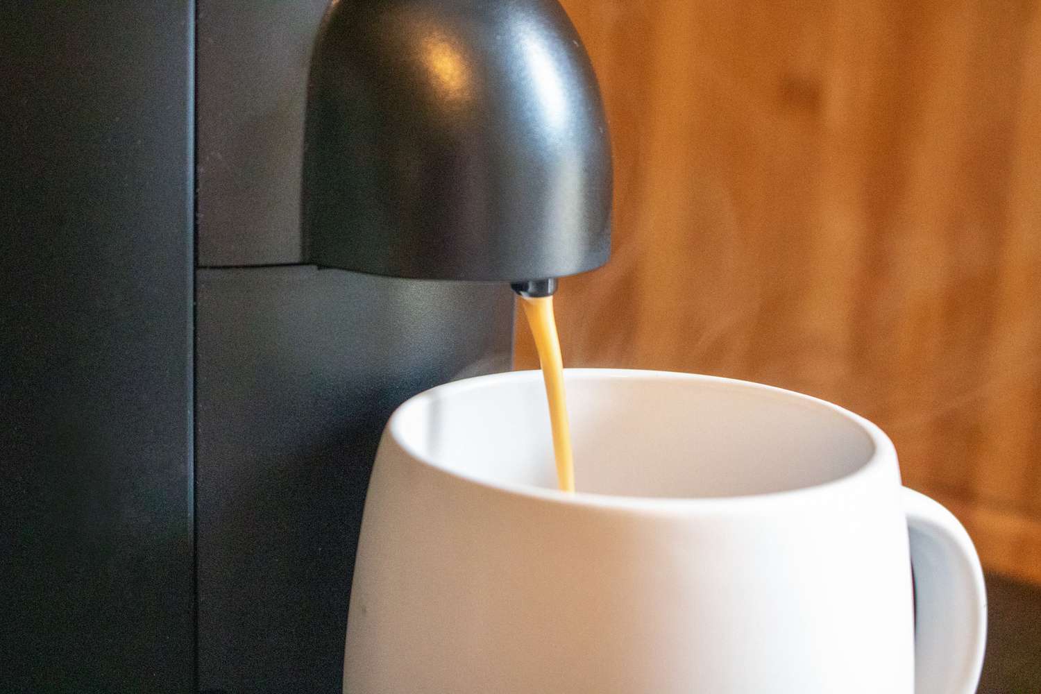 A closeup shot of a Nespresso machine brewing into a white mug