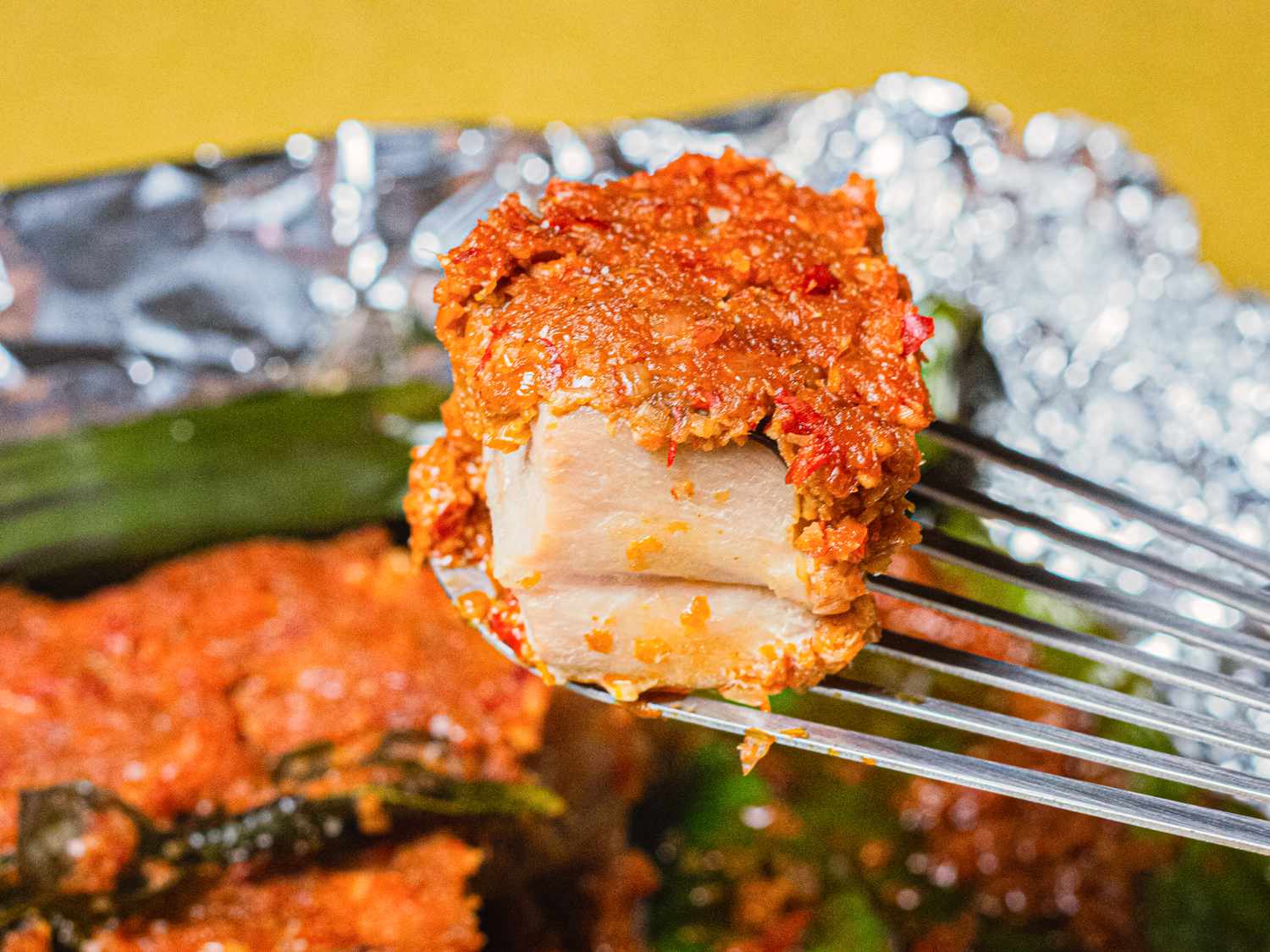A fish spatula lifting up a bite of sambal stingray
