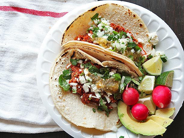 Chorizo tacos with avocado, radishes, and lime wedges on the side.