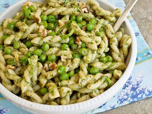 A bowl of gemelli pasta salad with peas, pesto, and chopped walnuts