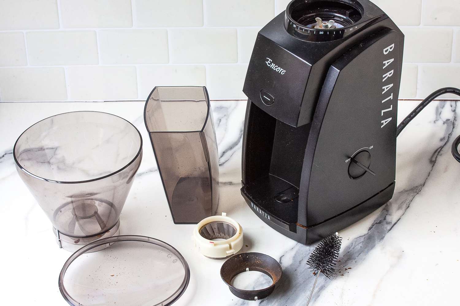 A disassembled coffee grinder with its parts spread out on a white surface