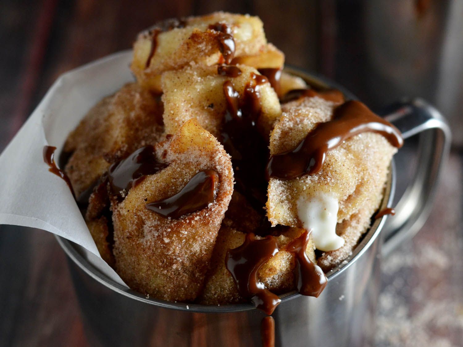 A closeup of the cream cheese wontons, coated in cinnamon sugar and drizzled with Nutella sauce.