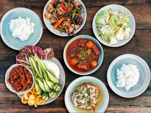 Overhead view of five Thai dishes, served with sticky rice.
