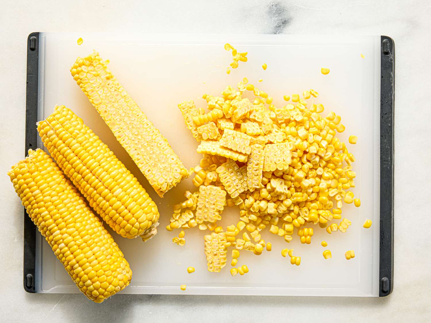 Corn on the cob with kernels sliced off shown on a cutting board