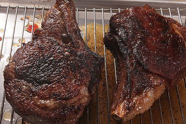 Two sous vide, pan-seared, and torched steaks resting on a rack.